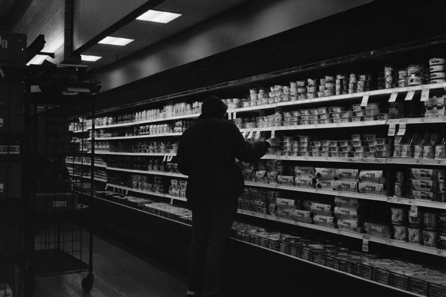 Person holding shopping basket paper list supermarket aisle
