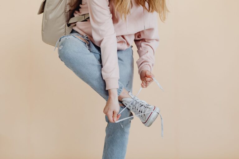 Woman tying white sneakers trousers shoe care brush