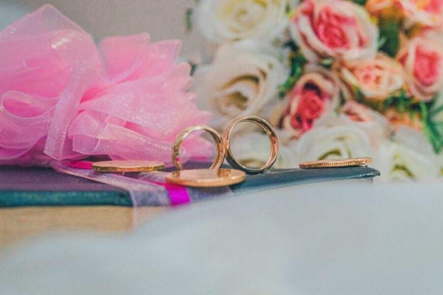 Close-up of gold wedding rings with a backdrop of roses, ideal for celebrating love.